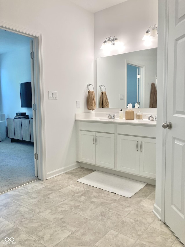 bathroom with double vanity, baseboards, and a sink