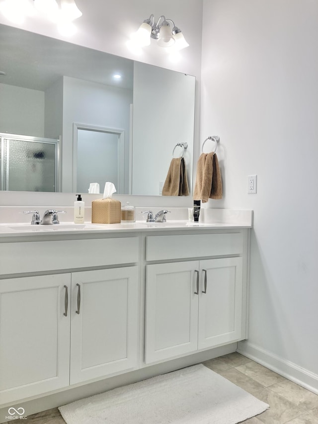 full bath with a sink, a shower stall, baseboards, and double vanity