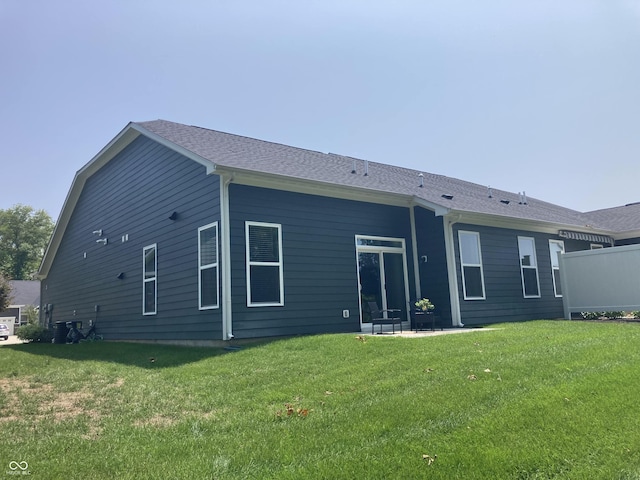 rear view of house with a yard and roof with shingles