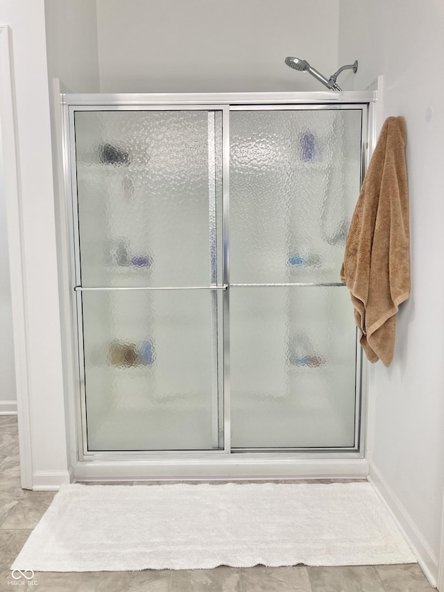 full bath featuring a shower with door and tile patterned floors