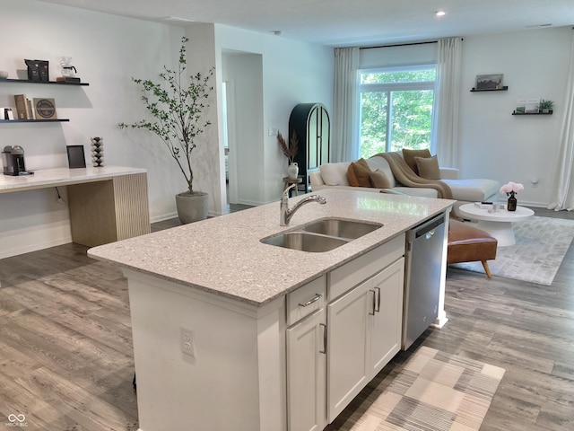 kitchen with a center island with sink, white cabinets, a sink, light stone countertops, and dishwasher