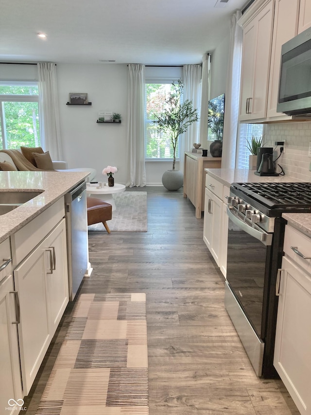 kitchen featuring white cabinetry, stainless steel appliances, and light stone counters