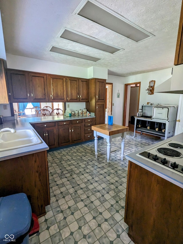 kitchen with a textured ceiling, tile patterned floors, white electric cooktop, and a sink