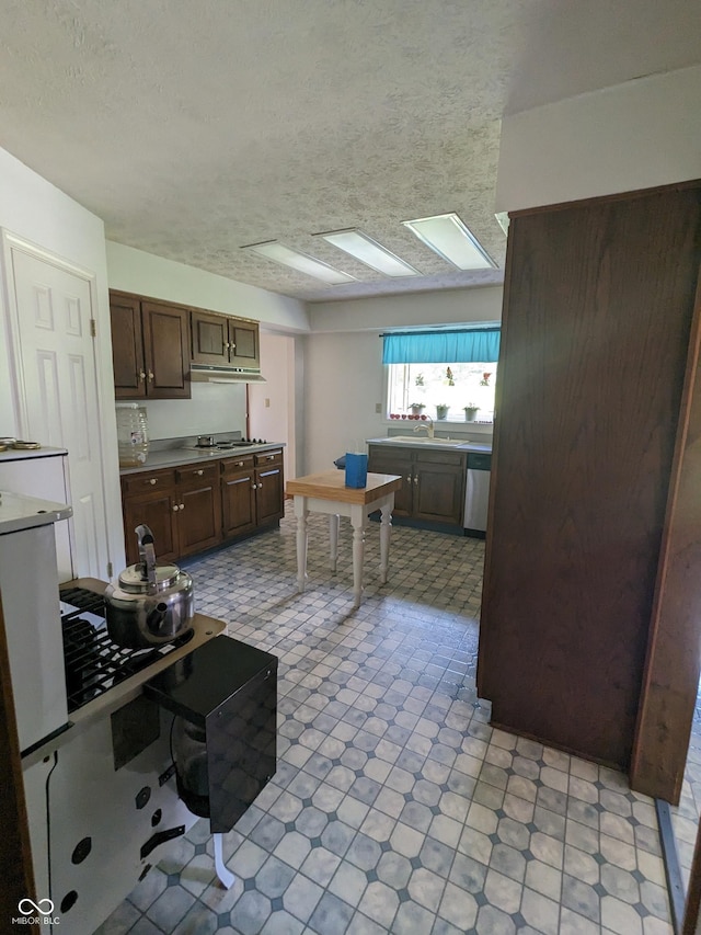 kitchen with cooktop, light floors, dishwasher, a sink, and a textured ceiling