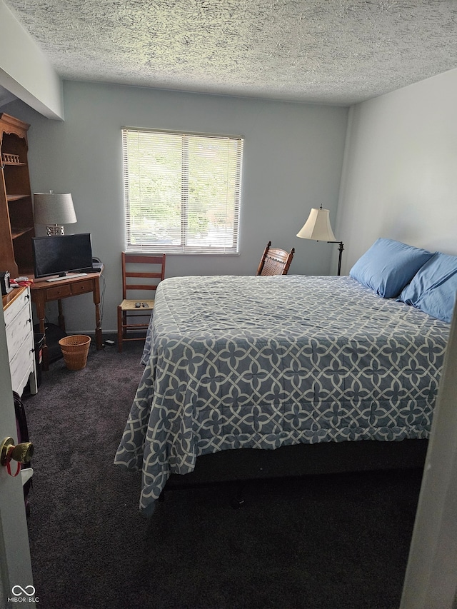 bedroom featuring dark colored carpet and a textured ceiling