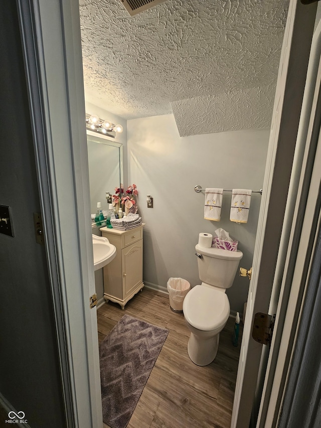 bathroom featuring vanity, toilet, a textured ceiling, and hardwood / wood-style floors