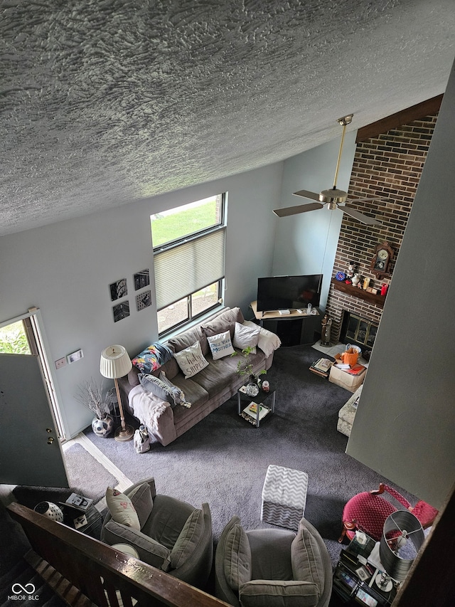 carpeted living room featuring a textured ceiling, ceiling fan, plenty of natural light, and a brick fireplace