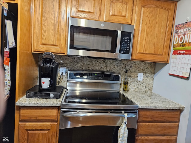 kitchen with decorative backsplash, light stone countertops, and stainless steel appliances