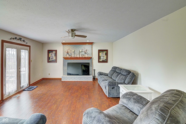 living room featuring hardwood / wood-style flooring, a textured ceiling, and a brick fireplace