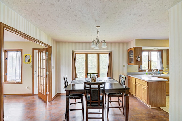 dining room with sink, dark hardwood / wood-style flooring, a textured ceiling, and a chandelier