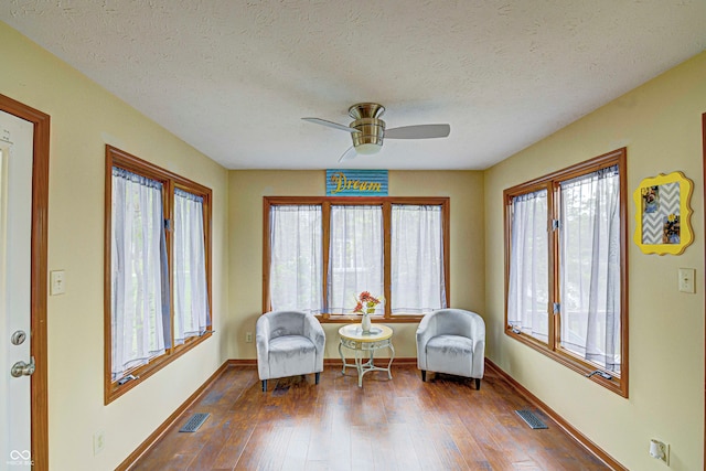 sitting room featuring hardwood / wood-style floors, a textured ceiling, ceiling fan, and a healthy amount of sunlight