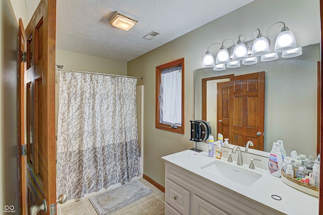 bathroom with vanity, a textured ceiling, and tile patterned flooring