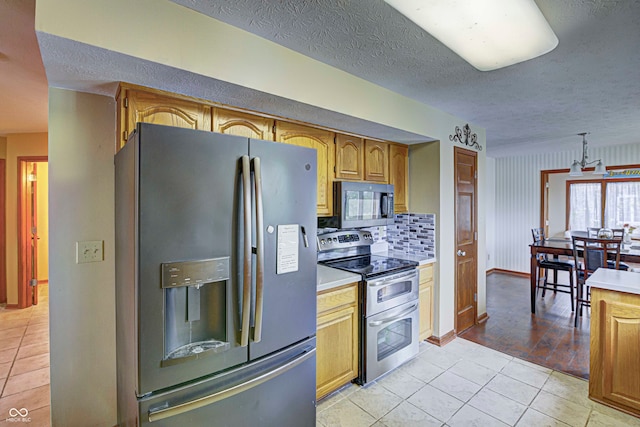 kitchen featuring stainless steel appliances, light hardwood / wood-style flooring, a textured ceiling, and decorative backsplash