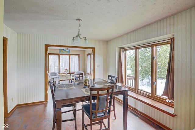 dining room with a textured ceiling, hardwood / wood-style floors, and a chandelier