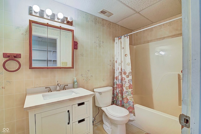 full bathroom with shower / tub combo, a paneled ceiling, tile patterned flooring, tile walls, and vanity