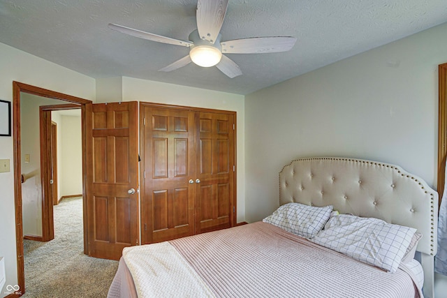 carpeted bedroom with a textured ceiling, a closet, and ceiling fan