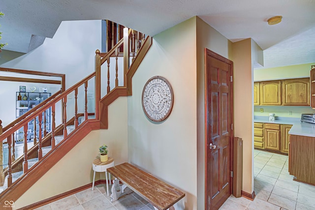 staircase with a textured ceiling and light tile patterned floors