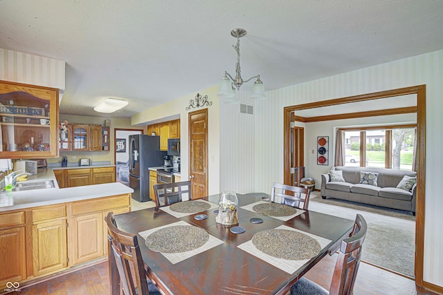 dining space featuring a notable chandelier, sink, and light hardwood / wood-style floors