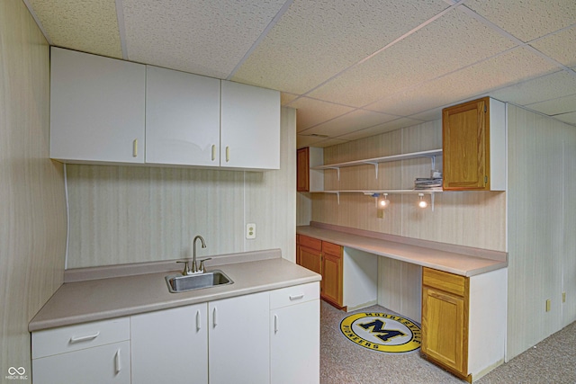 kitchen with white cabinets, a paneled ceiling, carpet, and sink