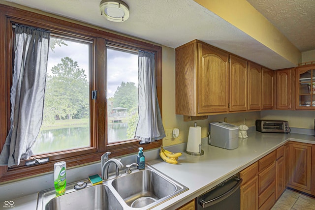 kitchen featuring black dishwasher, sink, a textured ceiling, and light tile patterned flooring