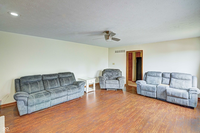 living room with ceiling fan, a textured ceiling, and wood-type flooring