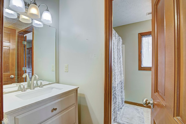 bathroom with a textured ceiling, tile patterned flooring, vanity, and an inviting chandelier