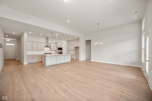 unfurnished living room featuring a notable chandelier and light hardwood / wood-style flooring