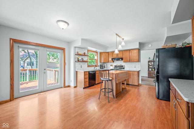 kitchen with black appliances, a kitchen island, french doors, backsplash, and hanging light fixtures