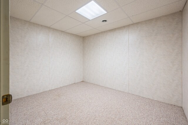 carpeted empty room with a paneled ceiling