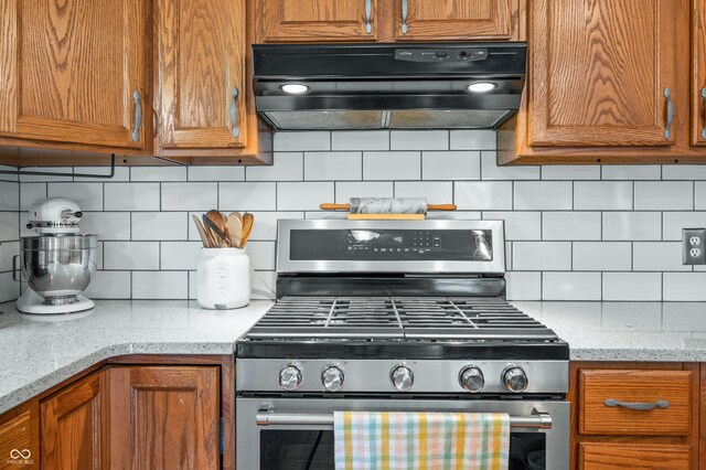 kitchen with stainless steel range with gas cooktop, light stone countertops, decorative backsplash, and range hood