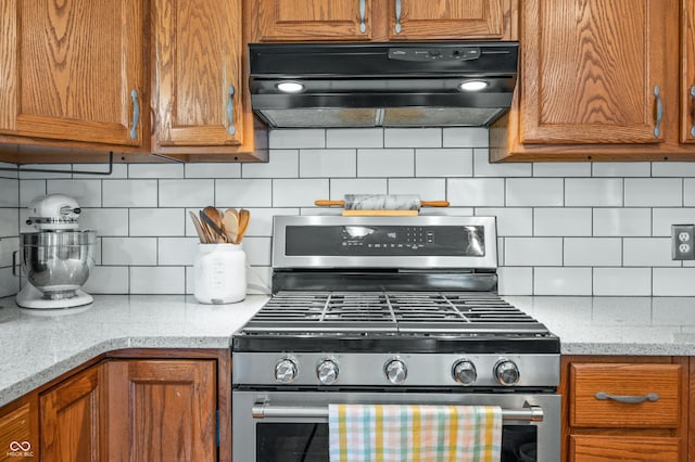 1936 Broadmoor Ln, Columbus, IN 47203 - kitchen with gas range, ventilation hood, tasteful backsplash, brown cabinets, and light stone countertops