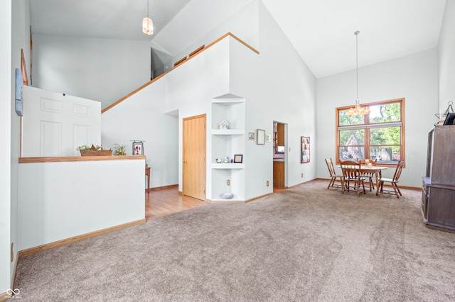 carpeted living room featuring a chandelier and high vaulted ceiling