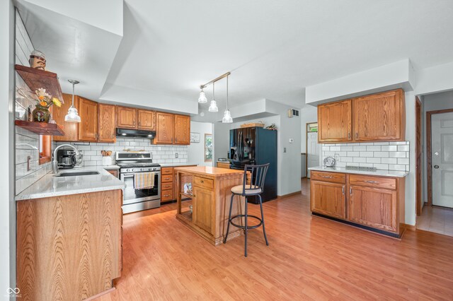 kitchen featuring stainless steel range, sink, light hardwood / wood-style floors, and a kitchen island