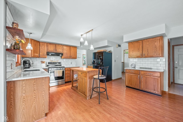 1936 Broadmoor Ln, Columbus, IN 47203 - kitchen featuring stainless steel gas range, under cabinet range hood, a sink, black refrigerator with ice dispenser, and decorative backsplash