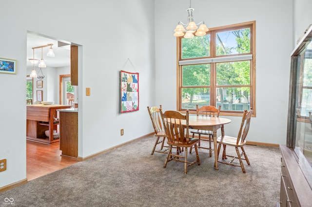 dining room featuring a towering ceiling, light hardwood / wood-style flooring, and a chandelier