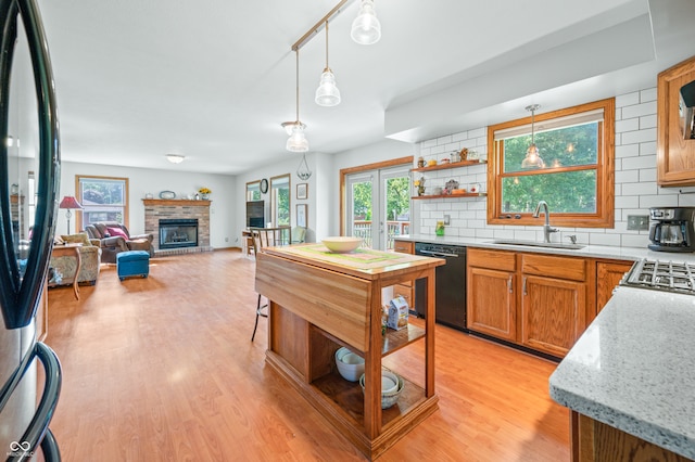 kitchen with hanging light fixtures, sink, black appliances, a fireplace, and tasteful backsplash