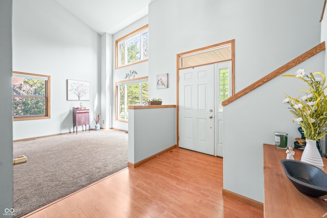 entryway with light hardwood / wood-style flooring and high vaulted ceiling