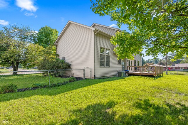 view of home's exterior with central air condition unit, a deck, and a lawn