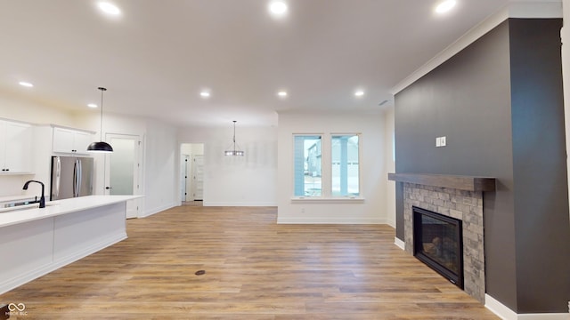 living room featuring a brick fireplace, crown molding, sink, and light wood-type flooring