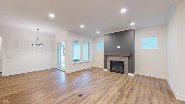 unfurnished living room with a healthy amount of sunlight, a chandelier, and light hardwood / wood-style floors