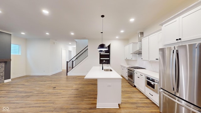 kitchen with sink, white cabinetry, decorative light fixtures, stainless steel appliances, and a kitchen island with sink