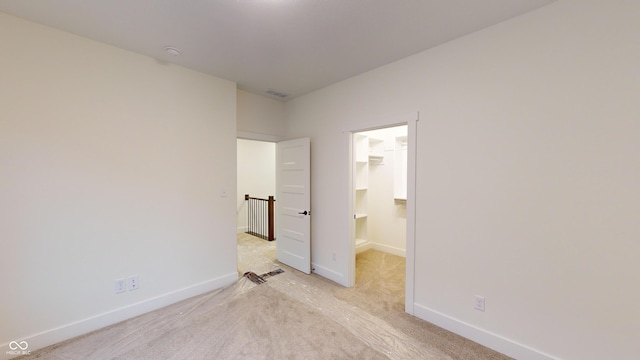 unfurnished bedroom with light carpet and a spacious closet