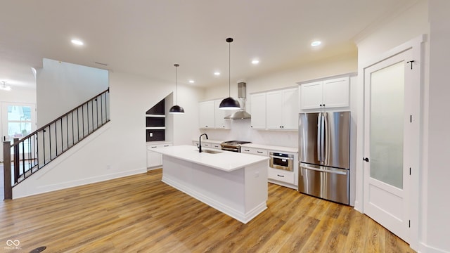 kitchen featuring sink, hanging light fixtures, a center island with sink, stainless steel appliances, and white cabinets