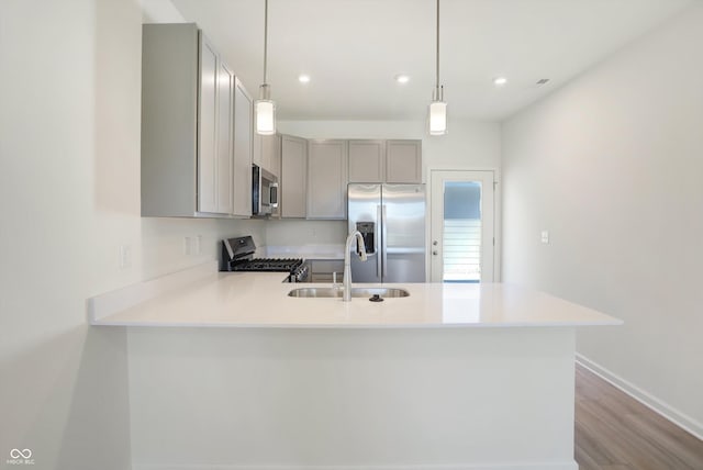 kitchen with sink, light hardwood / wood-style flooring, hanging light fixtures, stainless steel appliances, and kitchen peninsula