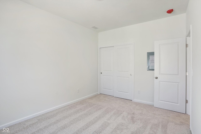 unfurnished bedroom with light colored carpet and a closet