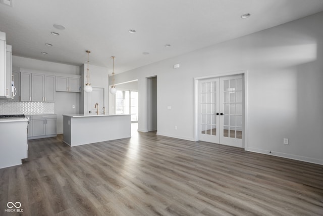 unfurnished living room featuring sink, dark wood-type flooring, and french doors