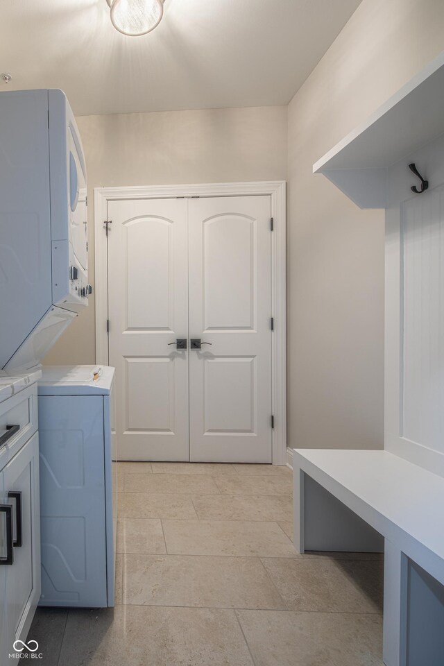 laundry room with stacked washer and dryer, cabinets, and light tile patterned floors