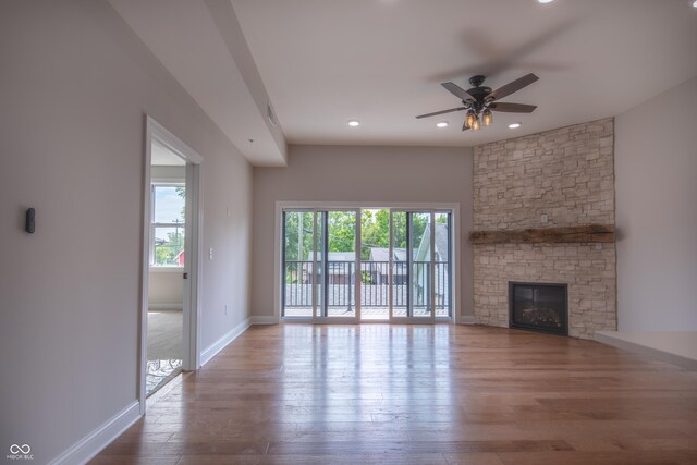 unfurnished living room with a wealth of natural light, a fireplace, wood-type flooring, and ceiling fan