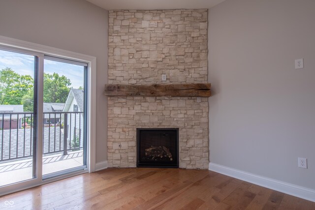 unfurnished living room featuring plenty of natural light, a stone fireplace, and hardwood / wood-style flooring