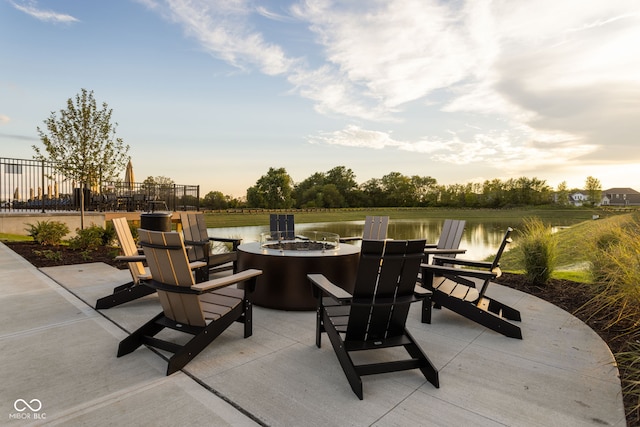 patio terrace at dusk with a water view and a fire pit